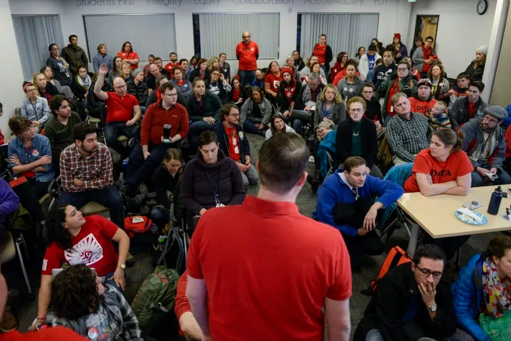 A man talks to a large crowd that appears stressed