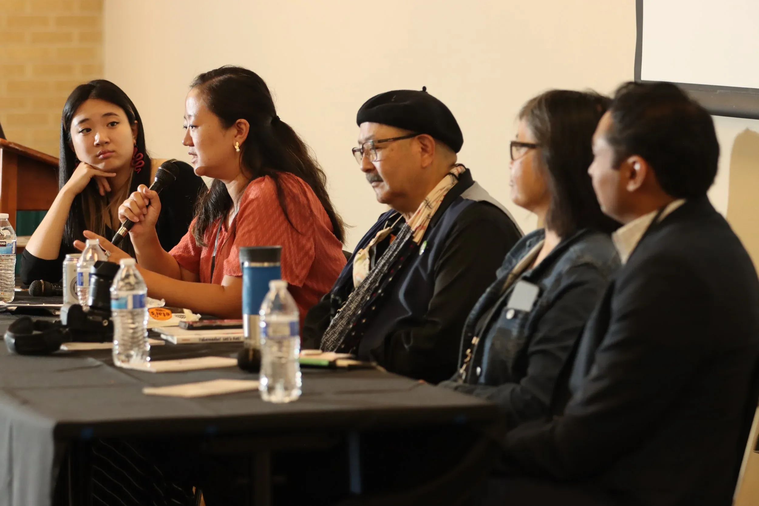 A group from the AANHPI Voices working group sit on a panel and talk into a microphone
