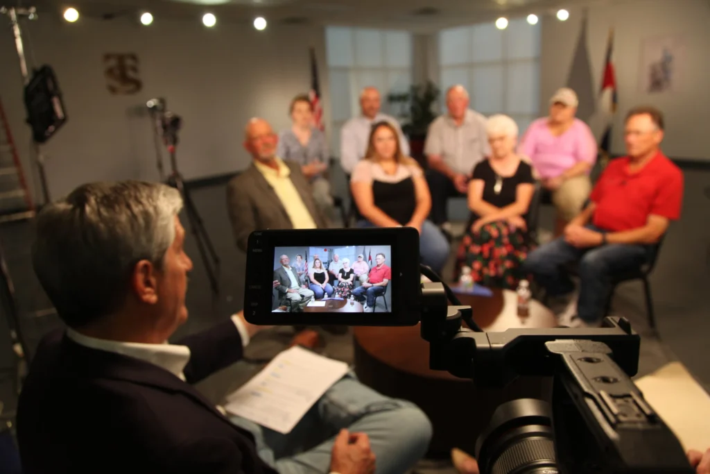 A camera focuses on a group of people being interviewed